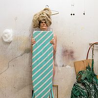 Kunstwerk von Christine Lederer: Eine leicht bekleidete Frau wo ein Bügelbrett vor sich hält.